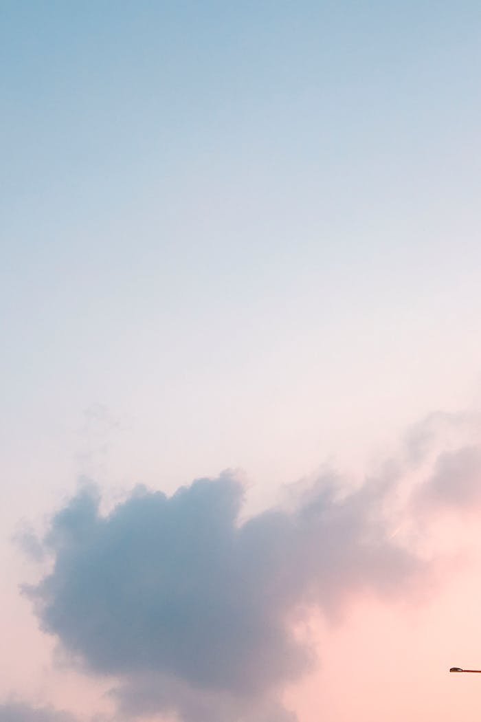 Calm pastel sky with soft clouds at sunset, creating a peaceful atmosphere.