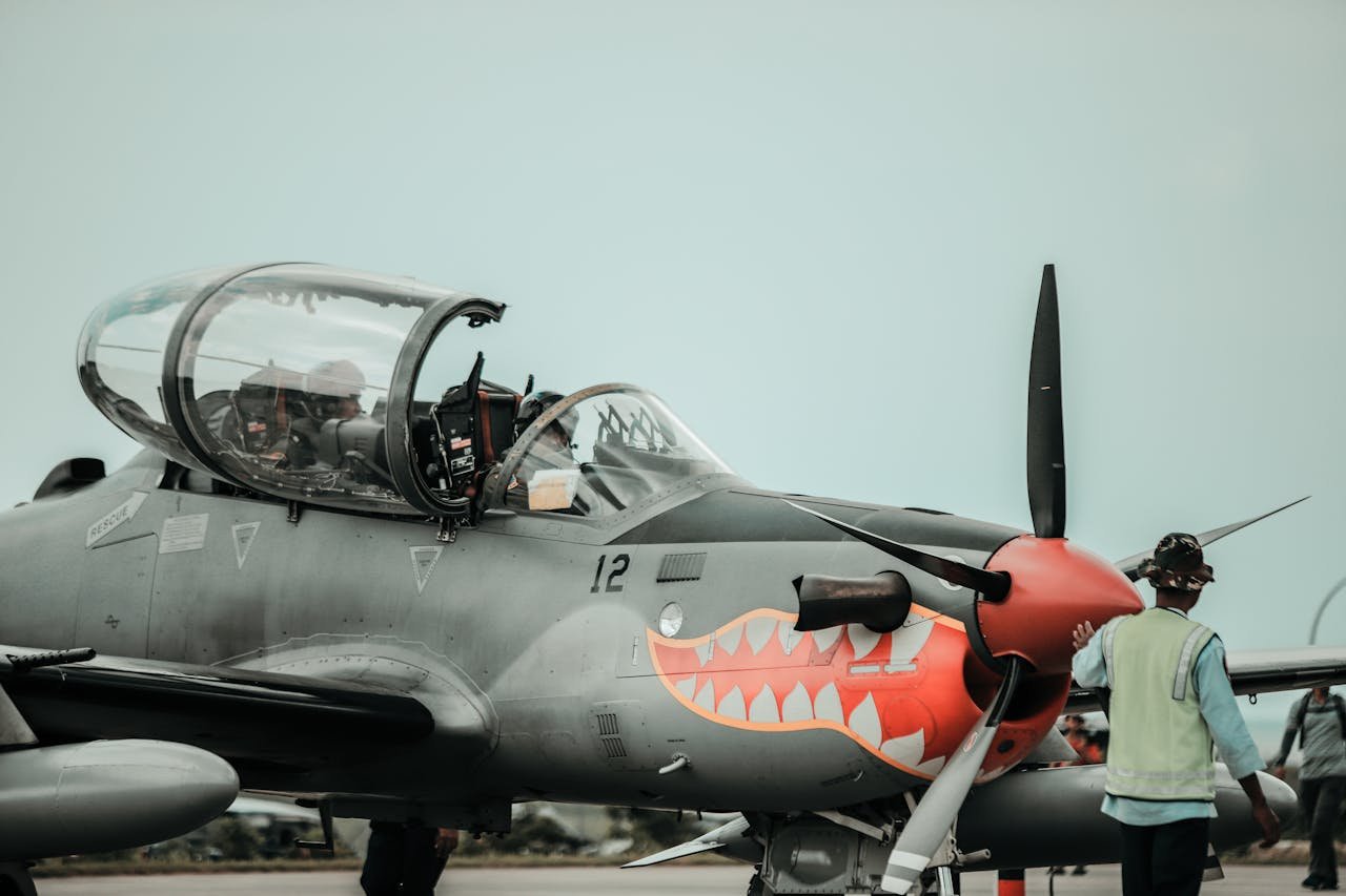 A detailed view of a military aircraft featuring shark teeth design on the runway with crew personnel.