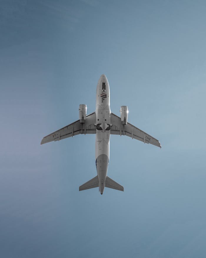 A commercial jet airplane viewed from below against a clear blue sky.